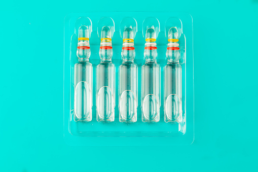 set of ampoules for vaccine injection in packaging on a blue background top view