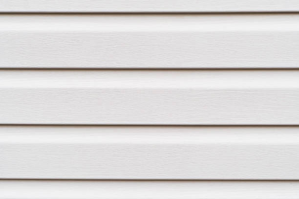 Construction vinyl siding panels pattern. House covered with white plastic vinyl siding. Vinyl siding wall surface with horizontal lines texture background. Wall covered with plastic beige siding.