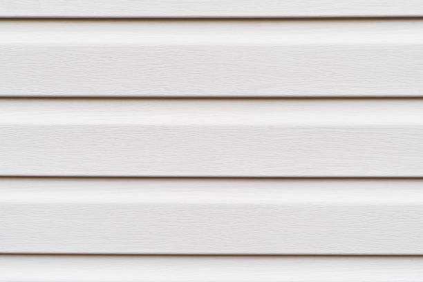 Construction vinyl siding panels pattern. House covered with white plastic vinyl siding. Vinyl siding wall surface with horizontal lines texture background. Wall covered with plastic beige siding. stock photo