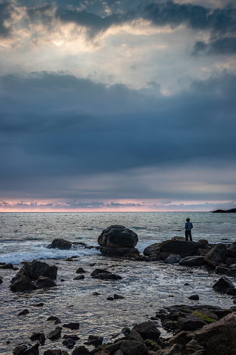 Man watching sea horizon from standing on rock at sunset point kanyakumari tamilnadu india.