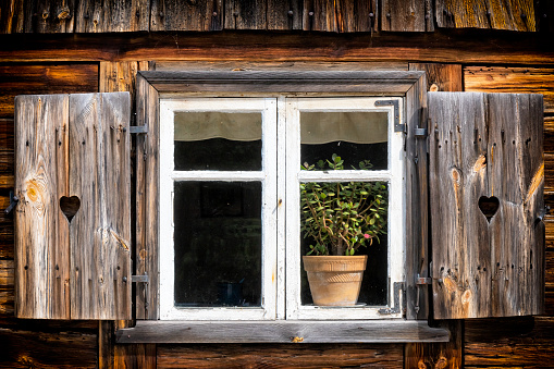 Old wooden cabin framed window looking out into green pasture. Vintage, rustic wood theme.