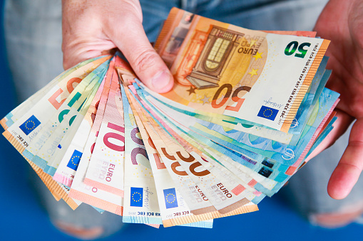 Many euro banknotes held in the hand
