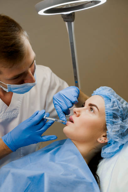 istock Lips augmentation injections for attractive girl. Plastic surgeon does injection in lip in medical clinic. Cosmetic rejuvenating facial treatment. Empty space for advert 1280931542