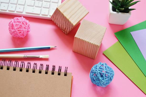 istock Flat lay designer workplace. Computer keyboard, sketchbook, pencil, brush, wooden cubes, rattan balls and colorful paper sheets 1280931978