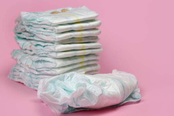 istock stack of diapers on a pink background, baby hygiene products. Selective focus 1280933949