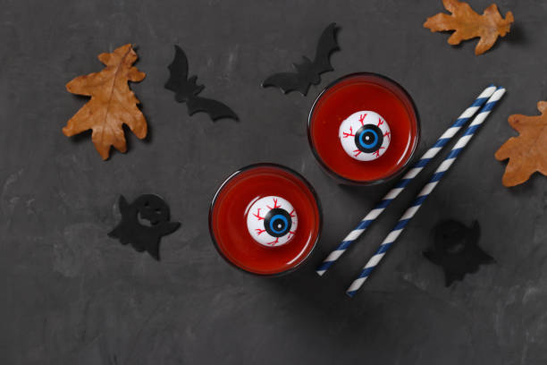 秋の休日のハロウィーンのための暗いテーブルの上にトマトカクテルとガラスの目。トップ ビュー。フラットレイ。 - glass autumn halloween food ストックフォトと画像