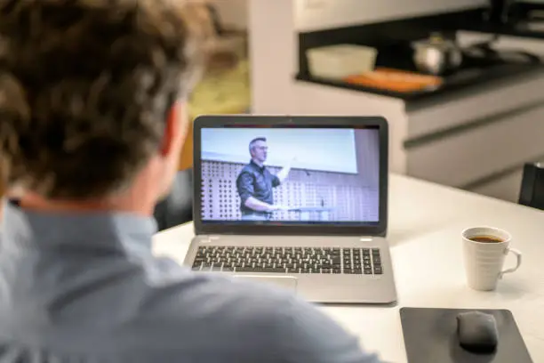 Photo of View over unrecognized man's shoulder on laptop computer screen.