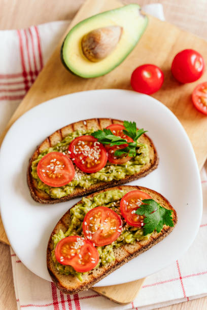 istock toasted bread with avocado paste and fresh tomato. Avocado mixed with lemon juice is spread on bread.  health food concept, vegan, vegetarian 1280937034