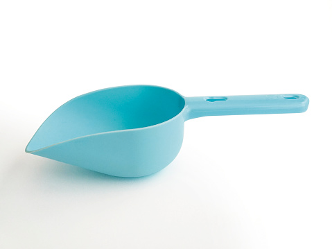 Blue plastic pet food shovel isolated on white background. Empty plastic dog and pet food spatula, spoon for dry food, measuring feeding accessories for puppies.