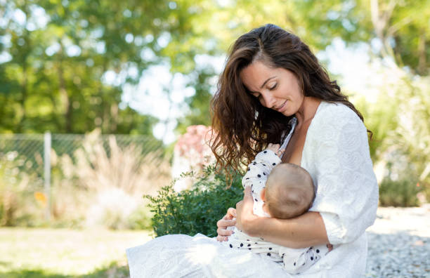Woman nursing baby girl outdoors in backyard. Portrait of woman nursing baby girl outdoors in backyard. breastfeeding photos stock pictures, royalty-free photos & images