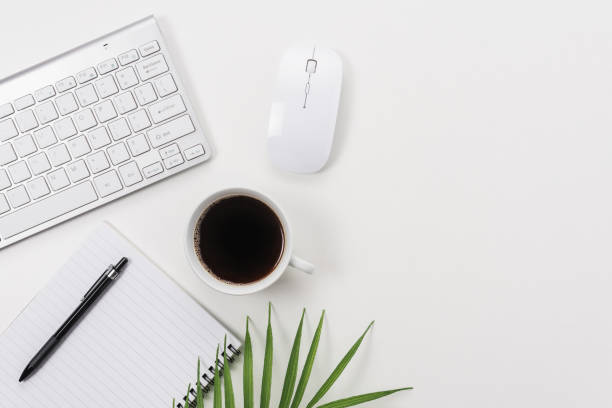 istock Workspace with computer keyboard, office supplies, green leaf, and coffee cup on white background. 1280941165