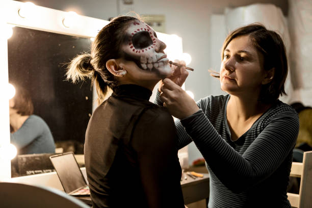 profesional maquillaje artista pintura cara de una mujer para la fiesta de la noche de halloween - skull holding spooky horror fotografías e imágenes de stock