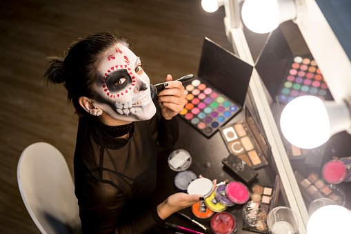 Woman painting face for Halloween night party