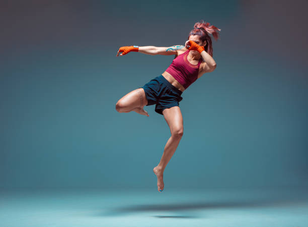 A young female fighter performs a jump kick. A young female fighter performs a jump kick. High quality photo mixed martial arts photos stock pictures, royalty-free photos & images