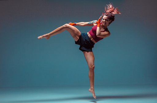 A young female fighter performs a jump kick. High quality photo