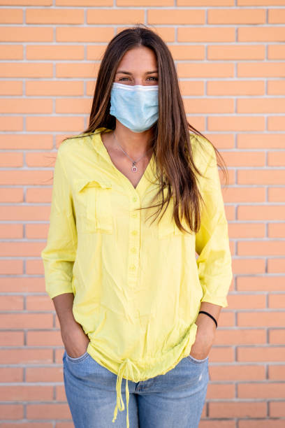 istock Young Woman With Hands in Pockets Wearing Protective Face Mask 1280946655