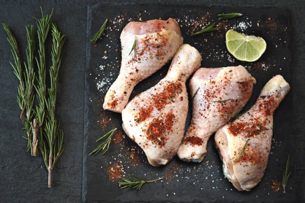 istock Raw chicken legs marinated in spices on a stone board. 1280952161