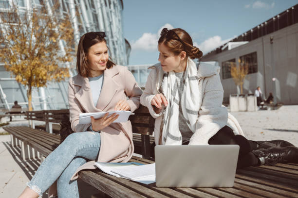 istock Two young women, college students, studying together outside 1280952316