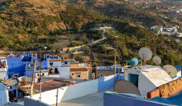 Photo of Blue roofs of the Chefchaouen town, Morocco. Medina of the Blue city on the side of the Rif mountains. Travel to North Africa. Numerous television antennas on the roofs of a residential buildings
