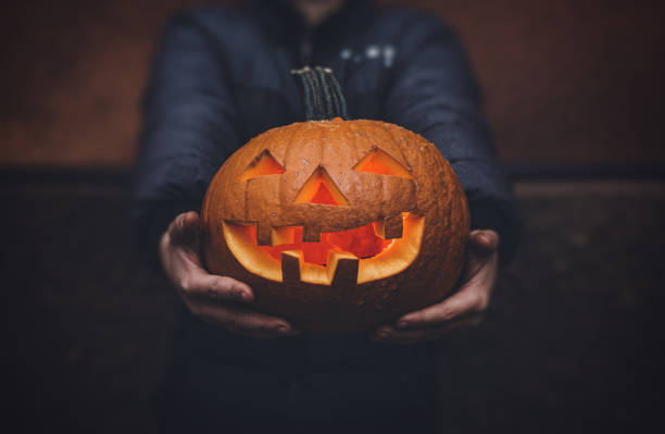 istock The boy is holding a Halloween pumpkin in his hands. Dark background. 1280955872