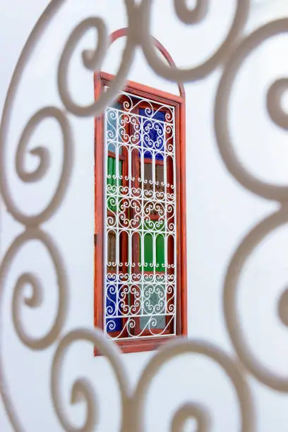 Photo of Window with multi-colored glass and arabic lattice in Marrakesh, Morocco. Moroccan authentic interior in medina quarter. Colorful oriental stained glass