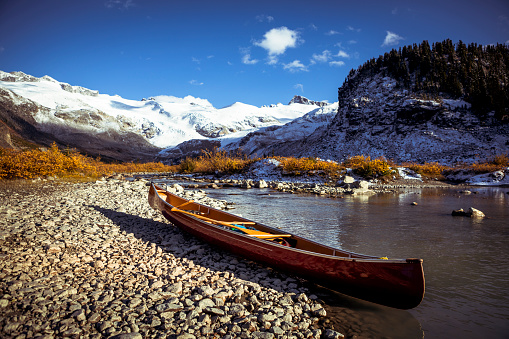 Empty red canoe on water’s edge in backcountry alpine.