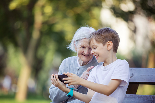 Young boy and his great grandmother using smartphone to make video call or take selfie. Streaming online video call. Mobile internet. Watching video on smartphone.