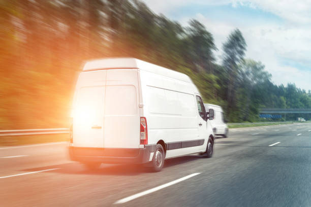 istock White modern delivery small shipment cargo courier van moving fast on motorway road to city urban suburb. Business distribution and logistics express service. Mini bus driving on highway on sunny day 1280960929