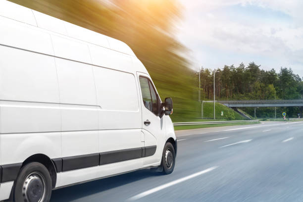 white modern delivery small shipment cargo courier van moving fast on motorway road to city urban suburb. busines distribution and logistics express service. mini bus driving on highway on sunny day - business speed horizontal commercial land vehicle imagens e fotografias de stock