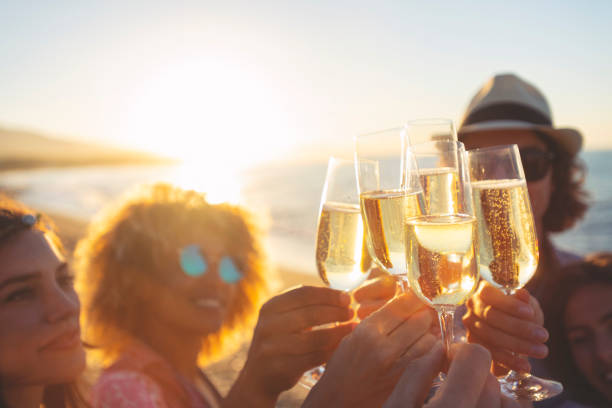 gruppo di amici che fanno un brindisi di champagne sulla spiaggia. - champagne celebration glass black foto e immagini stock