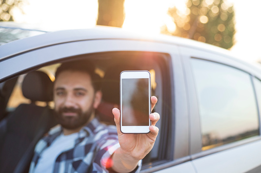 Portrait of handsome man holding phone in car