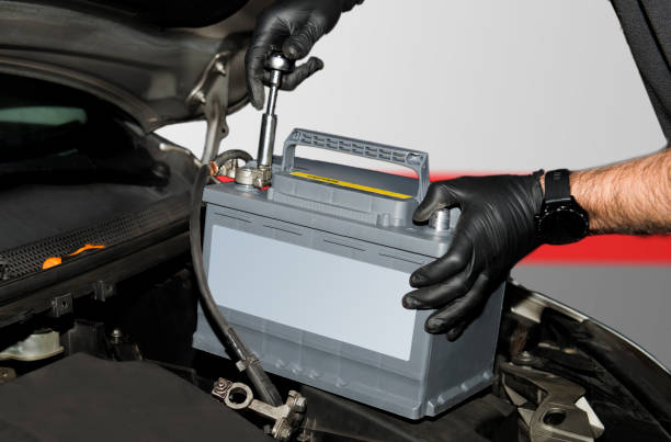 lavoratore mettendo una nuova batteria in un'auto diesel. - battery replacement foto e immagini stock