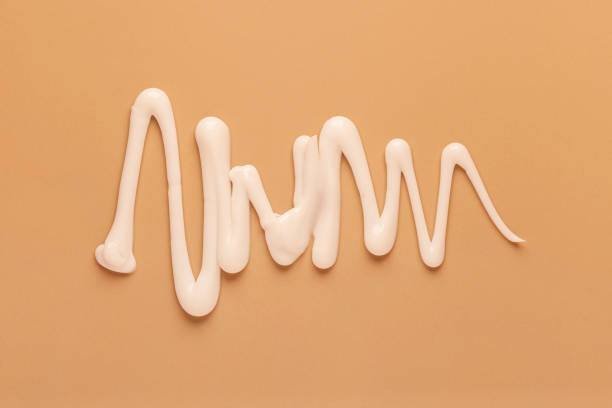 Squeezed out light cosmetic silky cream milk texture on caramel beige brown background