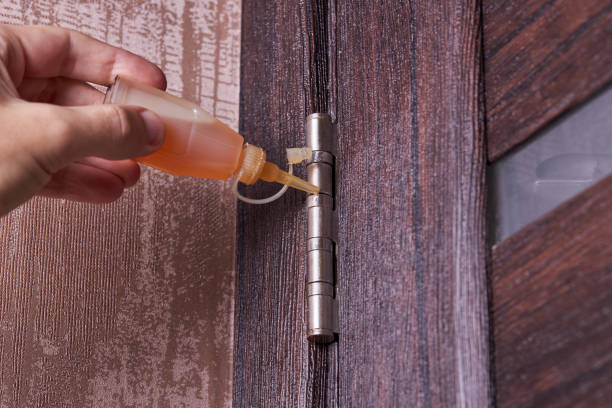 adjusting door hinge using lubricating oil. indoors. fixing door squealed domestic problem stock photo