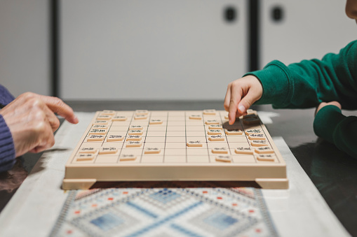 Japanese mulit generation family spending new year's holiday. Japanese senior man and boy playing shogi, Japanese traditional board game, together.