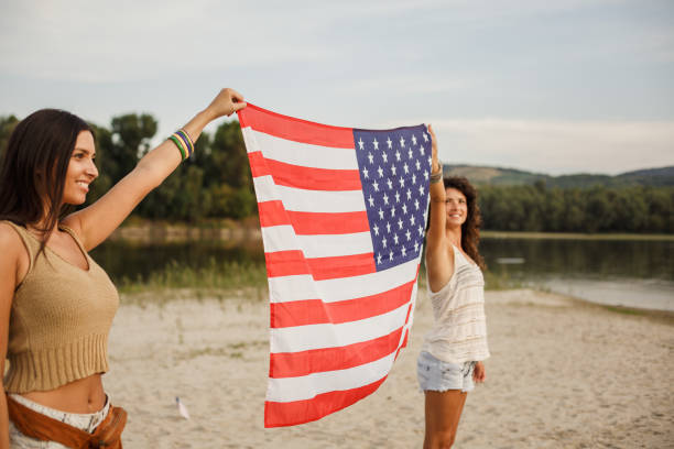 istock Girlfriends holding American flag while celebrating 4th of July 1280973412