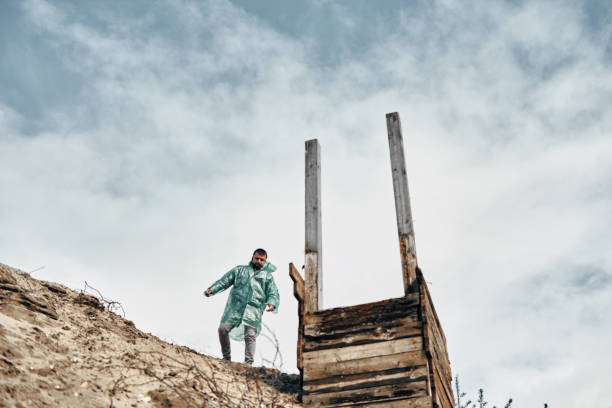 abandonné puits en bois sur le sable et un homme près du puits dans un imperméable, ciel nuageux. recherche de lieux abandonnés. - 11242 photos et images de collection