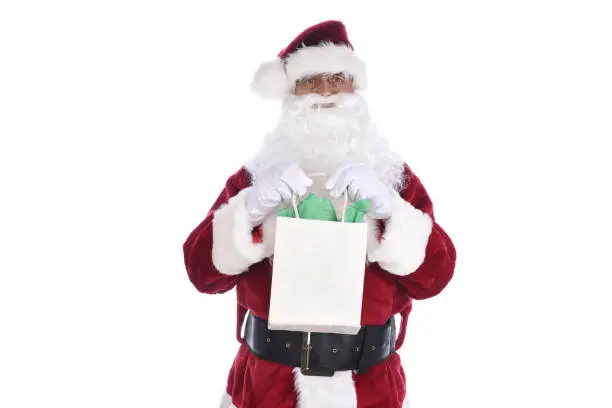 Senior man wearing a traditional Sant Claus costume holding a gift bag in both hands. Isolated on white.