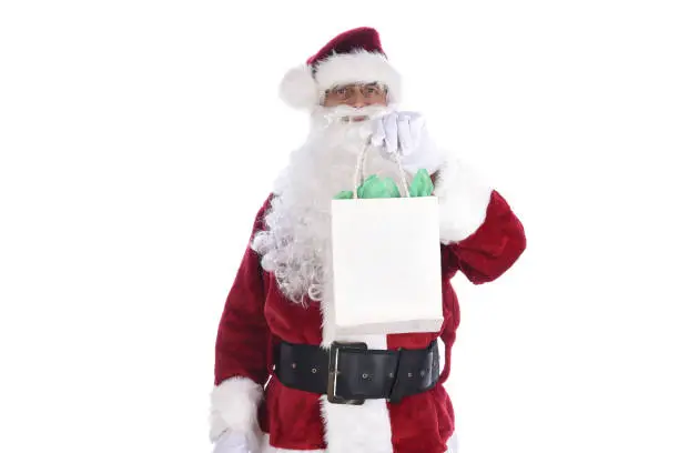 Senior man wearing a traditional Sant Claus costume holding a gift bag in his hand. Isolated on white.