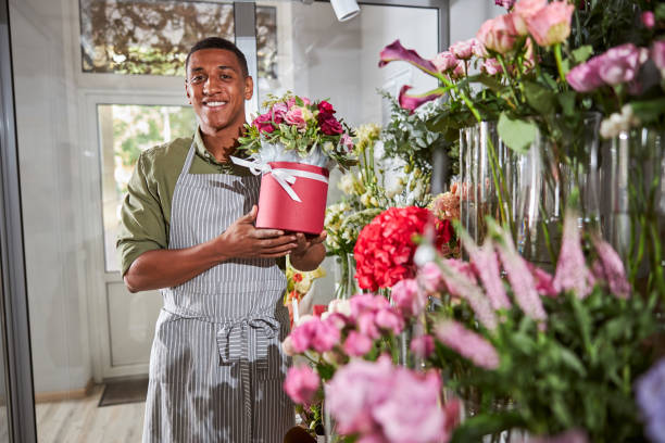 istock Friendly florist displaying a pot beside the flower rack 1280979313