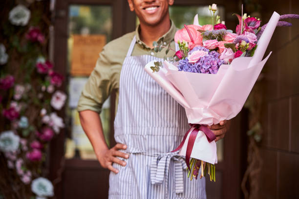 istock Nice flower shop worker demonstrating wrapped flowers 1280979346