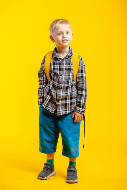 istock schoolboy with his arms crossed on yellow background 1280981084
