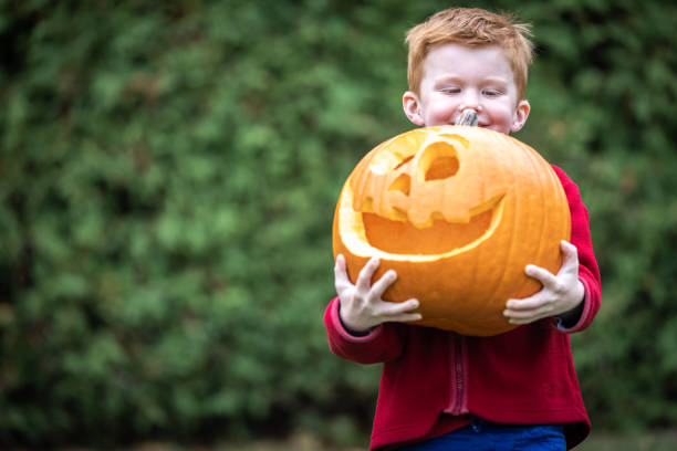 istock Child holding heavy Jack O' Lantern 1280982540