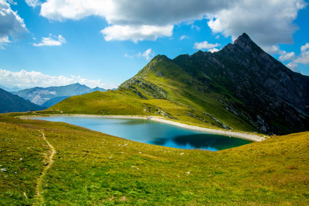 istock Grass-covered mountain peak behind a blue lake 1280983555
