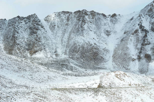 istock A road is barely visible as it crosses snow-covered mountains 1280985962