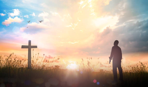 Worship God concept Silhouette christian standing over cross meadow sunset background easter sunday photos stock pictures, royalty-free photos & images