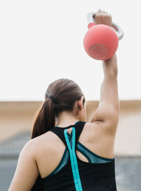 istock Back view of young woman lifting weight 1280986852