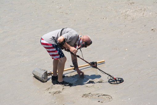 Myrtle Beach, United States - July 2nd, 2020: A man on Myrtle beach uses a metal detector in the sand