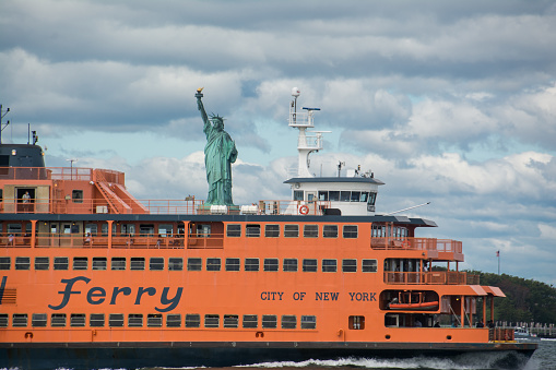 Governors Island, New York, United States - August 9th, 2020: A view of the Staten Island Ferry and the Statue of Liberty on the Hudson river