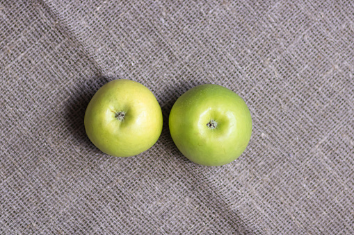 Top view to two green apples on canvas background. Copy space.